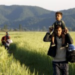 Seorang imigran Afghanistan membawa putranya, diikuti oleh istrinya saat mereka berjalan melewati sebuah ladang di dekat perbatasan Yunani-Makedonia dari desa perbatasan Idomeni di prefektur Kilkis, Yunani. Reuters/Yannis Behrakis